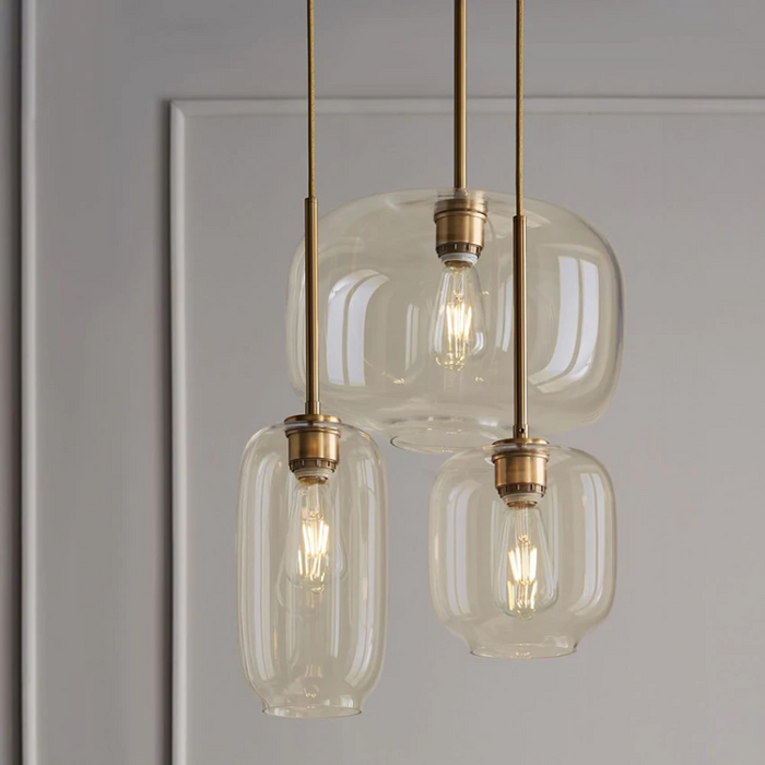 Brass and glass sculpted pendant lights with gold fittings clear and cognac glass shades three sizes hanging at varied lengths