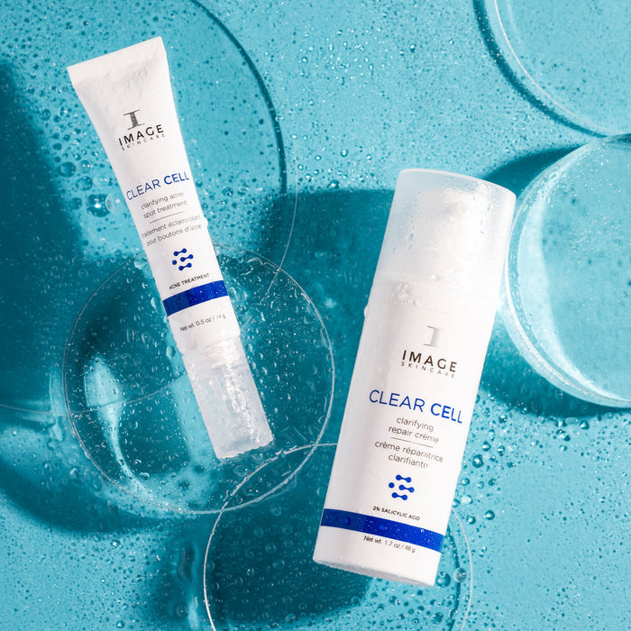 CLEAR CELL clarifying acne spot treatment and repair creme product bottles on blue background with bubbles