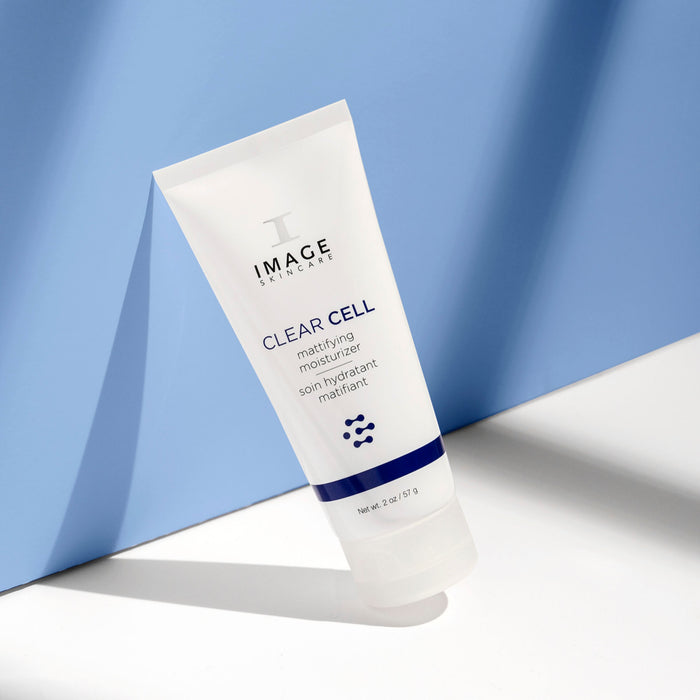 clear cell mattifying moisturizer bottle leaning against blue wall