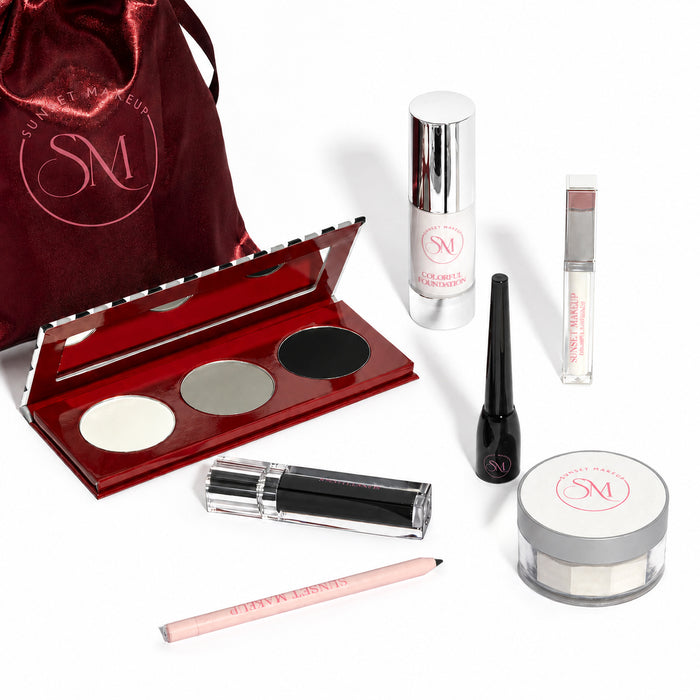 Sunset Makeup Goth Bundle Grand Edition makeup gift set with seven goth makeup essentials for a white base, black lips, eyeliner, highlighting, and contouring, arranged with a satin burgundy pouch.