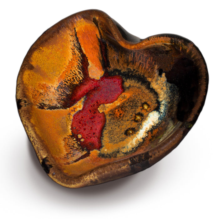 Heart-shaped bowl in toasted orange and black with red accents. Handmade pottery by Prairie Fire Pottery.  3/4 view.