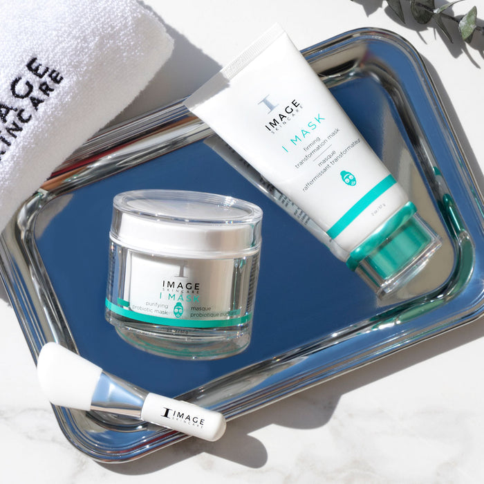 Skincare products including a jar and tube labeled 'IMAGE' on a reflective surface.
