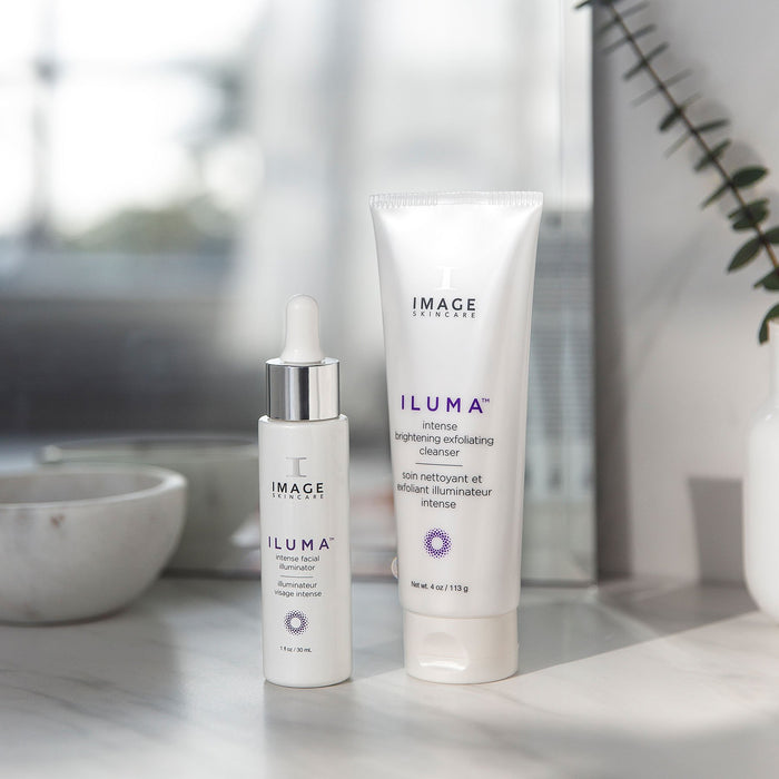 iluma intense facial illuminator bottle and exfoliating cleanser tube on bathroom counter
