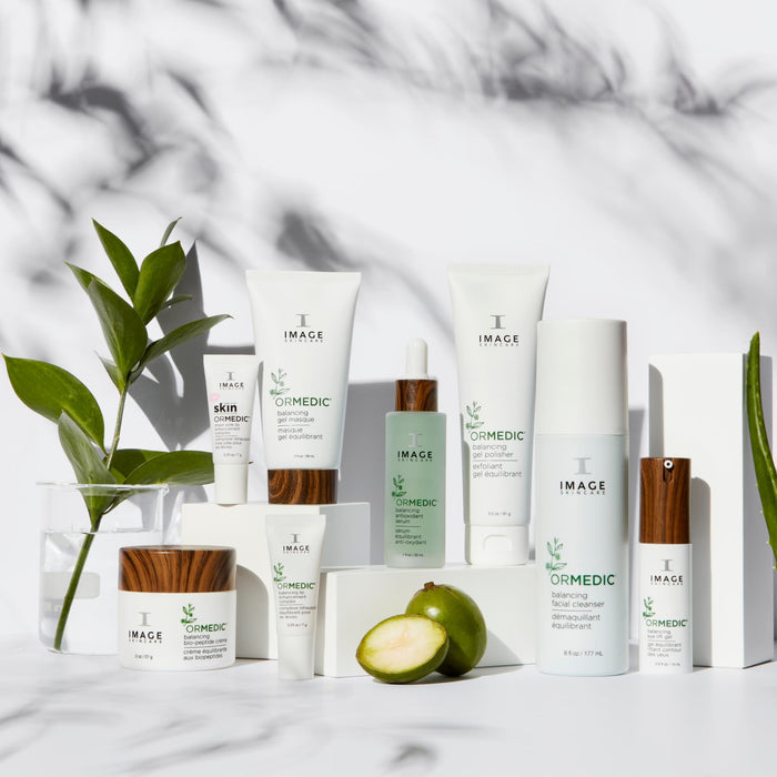 Full ormedic product collection on marble background with green plant and a sliced fruit surrounding products