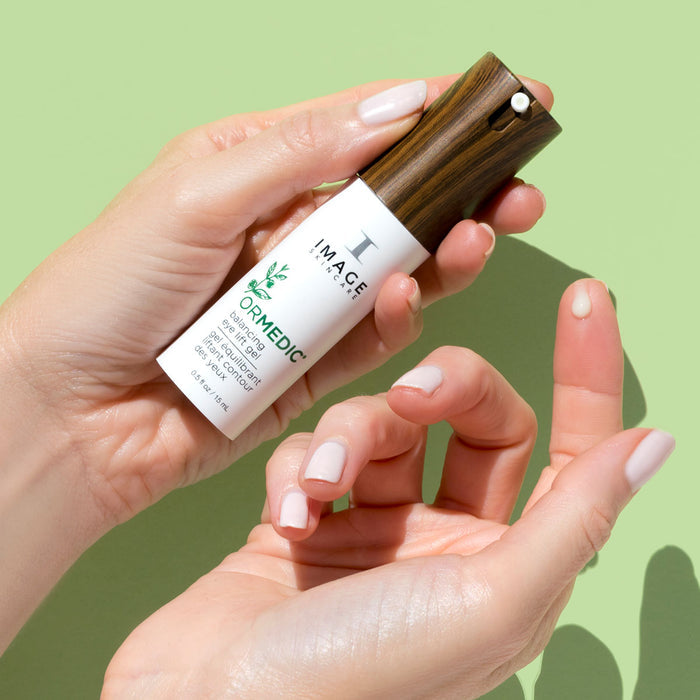 model hands holding product bottle dispensing product dot on finger