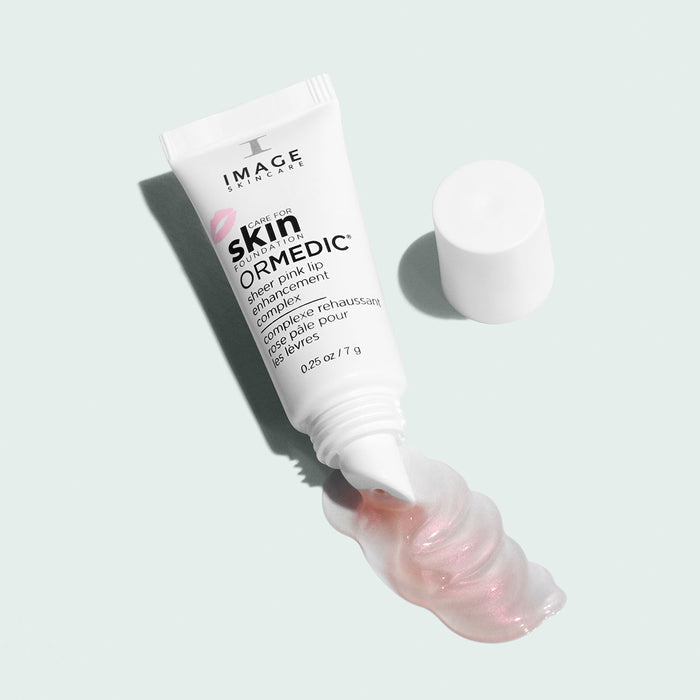 open tube of sheer pink lip complex with product pouring out on light background