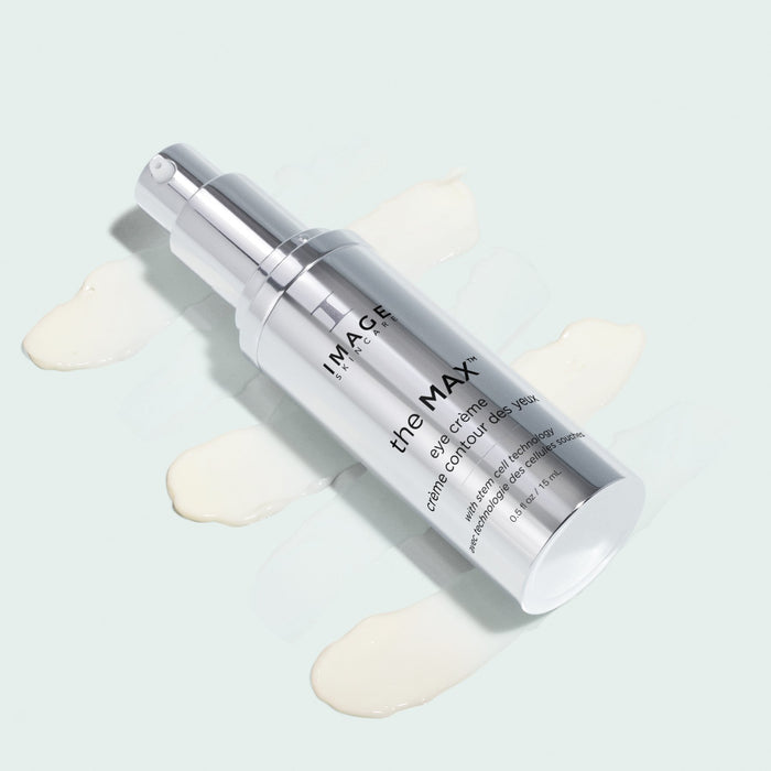 eye creme bottle opened laying on top of creme swatches on light background