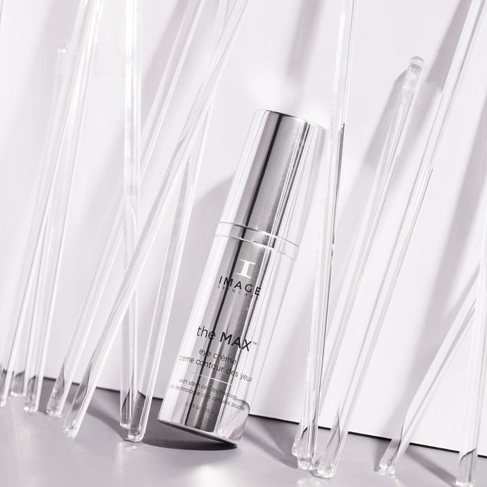 max eye creme bottle leaning against white wall surrounded by stirrers