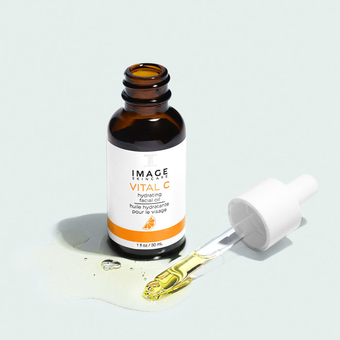 vital c facial oil dropper open with oil texture shot on light background