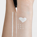Sunset Makeup white felt-tip eyeliner creating opaque white lines, a heart, and dots on skin.